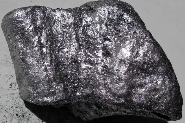 Kiiltävä grafiittimineraalinäyte harmaalla taustalla
